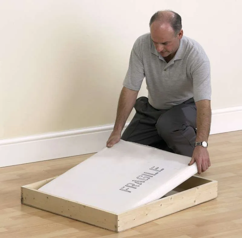 Mover securing a framed item in a custom wooden crate